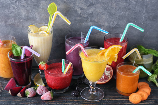 Glassware with different smoothies on table against grey background