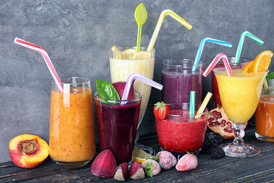 Glassware with different smoothies on table against grey background