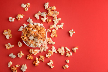 Cup with tasty caramel popcorn on color background