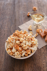 Bowl with tasty caramel popcorn on wooden table