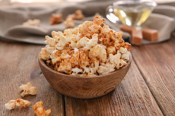 Bowl with tasty caramel popcorn on wooden table
