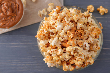 Bowl with tasty caramel popcorn on wooden table