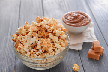 Bowl with tasty caramel popcorn on wooden table