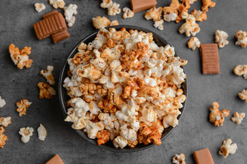 Bowl with tasty caramel popcorn on dark grey background