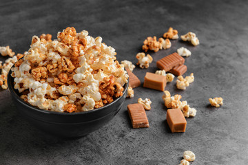 Bowl with tasty caramel popcorn on dark grey background