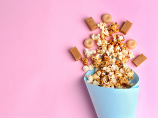 Paper cone with tasty caramel popcorn on color background