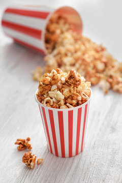 Cup with tasty caramel popcorn on wooden table