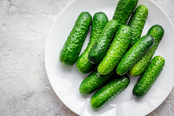 Fresh cucumbers on plate on grey background top view copyspace