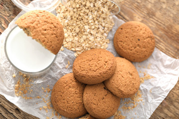 Delicious oatmeal cookies and glass of milk on wooden table
