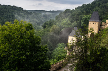 Fototapeta na wymiar Mist over the Karlstejn castle hidden in the forest, Czech Republic