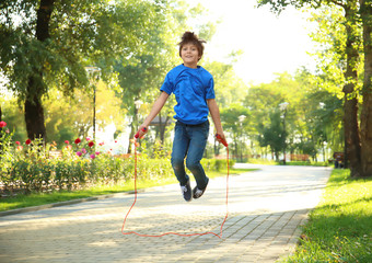 Cute little boy jumping rope in park