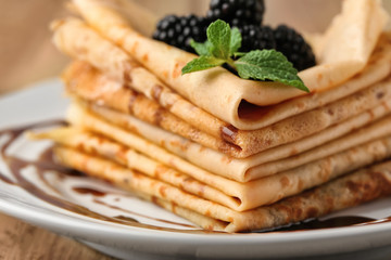 Delicious thin pancakes and berries on plate, closeup
