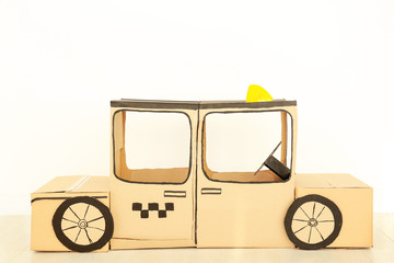 Cardboard taxi on white wall background