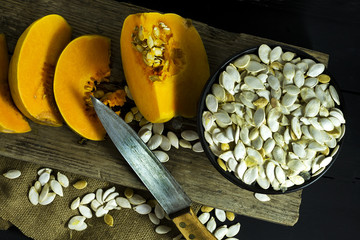 Sliced ripe pumpkin in a white plate with seeds and a wooden spoon. Harvest. Autumn.