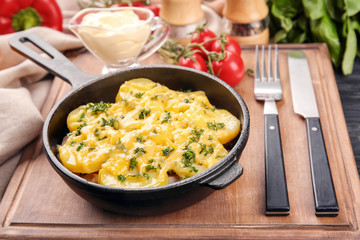 Pan with delicious potato casserole on wooden board