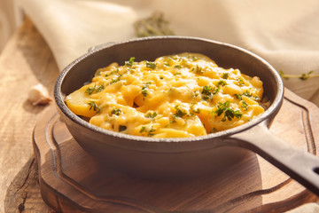 Board with delicious potato casserole in pan on table
