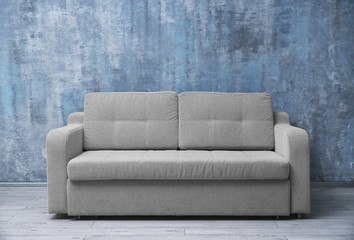 Comfortable sofa against color wall indoors