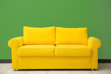Bright yellow sofa against green wall indoors