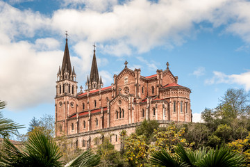 Fototapeta na wymiar Basilica of Santa Maria la Real de Covadonga, Asturias, Spain, Europe. Beautiful church touristic travel destination landmark with a vibrant colorful sky and green natural foliage.