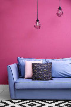 Comfortable sofa against pink wall indoors