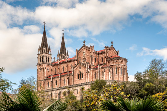 Basilica of Santa Maria la Real de Covadonga, Asturias, Spain, Europe. Beautiful church touristic travel destination landmark with a vibrant colorful sky and green natural foliage.
