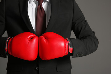 Businessman in boxing gloves on grey background