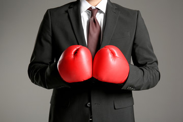 Businessman in boxing gloves on grey background