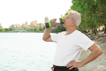 Sporty senior man drinking protein shake, outdoors