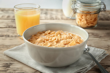 Dish with cornflakes and milk on table