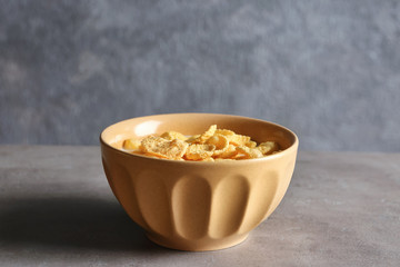 Dish with cornflakes and milk on table