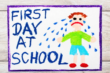 Obraz na płótnie Canvas Photo of colorful drawing: Words FIRST DAY AT SCHOOL and sad crying little boy