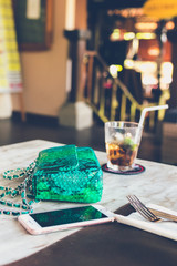 Fashion luxury snakeskin python handbag on the wooden table in restaurant. Bali island.