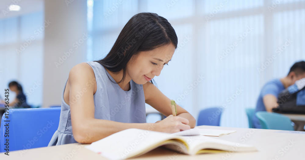 Wall mural Young woman studying at library