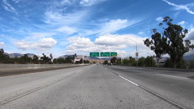 Slow motion driving shot of Pasadena and Sacramento overhead highway signs at the 118 and 210 freeway interchange in Los Angeles, California.  
