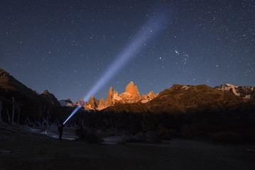 Traveler lantern shines in night sky near Mount Fitz Roy lit by moonlight. Patagonia, Argentina.