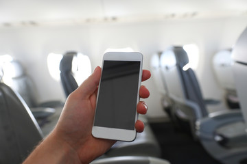 The man using mobile phone on the airplane while traveling