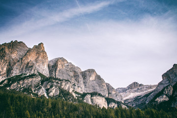Beautiful autumn landscape in Dolomites Italy, rural house between red and yellow trees with mountains