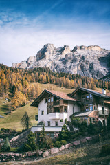 Fototapeta na wymiar Beautiful autumn landscape in Dolomites Italy, rural house between red and yellow trees with mountains