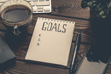 Goals list on notepad on work table, motivation strategy concept