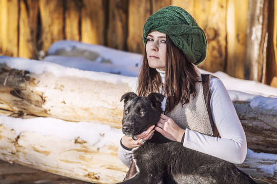 Portrait of a beautiful fashionable young woman and black dog in winter outdoor