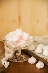Meringues in a cup on the wooden table, top view