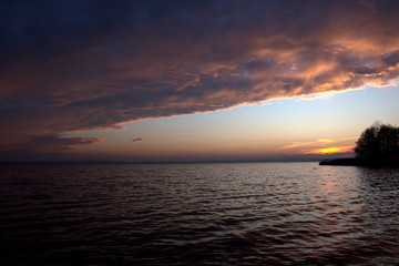 Fototapeta na wymiar Wolken beim Sonnenuntergang am See