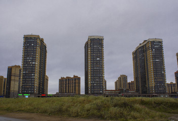 Fototapeta na wymiar New high-rise houses and a field of grass, a new district of the city built in the field, the view of the new building, the outskirts of the big city in the fall.