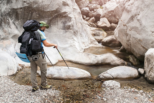 Backpacker man wading small mountain river in Goynuk canyon, lycian way, Turkey