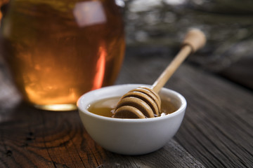 Honey in jar with honey dipper on wooden background 