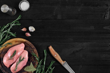 Raw chicken breast and condiments in a rustic wooden setting, top view