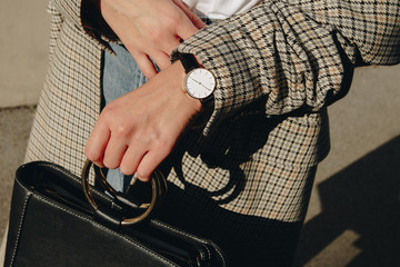 close up fashion details, young fashion blogger wearing black and white modern watch and a checked...