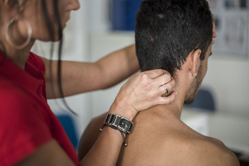 fisioterapista massaggia giovane paziente per curare un dolore cervicale