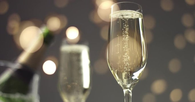 Bubbles going up in thin flute champagne glasses on a holiday table with a bottle of champagne in ice basket