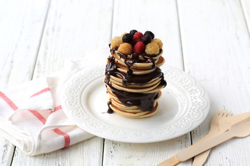 Banana pancakes with chocolate ganache and frozen berries